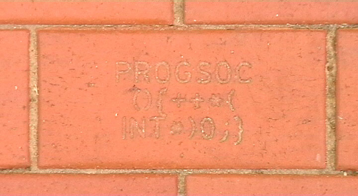 The ProgSoc C Function Brick. It contains K&R C source code of a function called PROGSOC whose sole job is to increment the value of a dereferenced integer pointer to address zero.